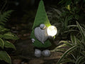 Magic orb garden gnome glowing among dark green plants