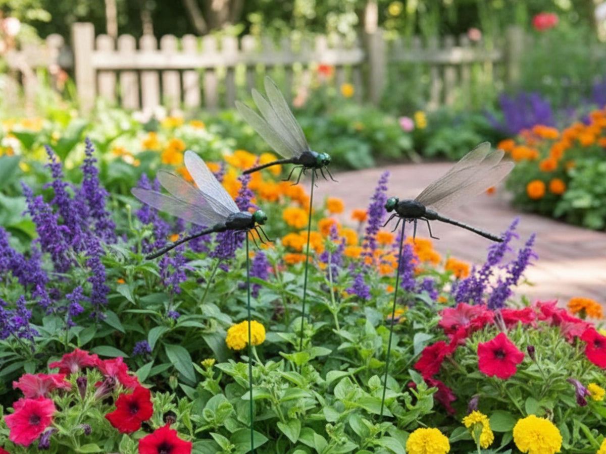 Three dragonfly garden stakes among purple red and yellow flowers