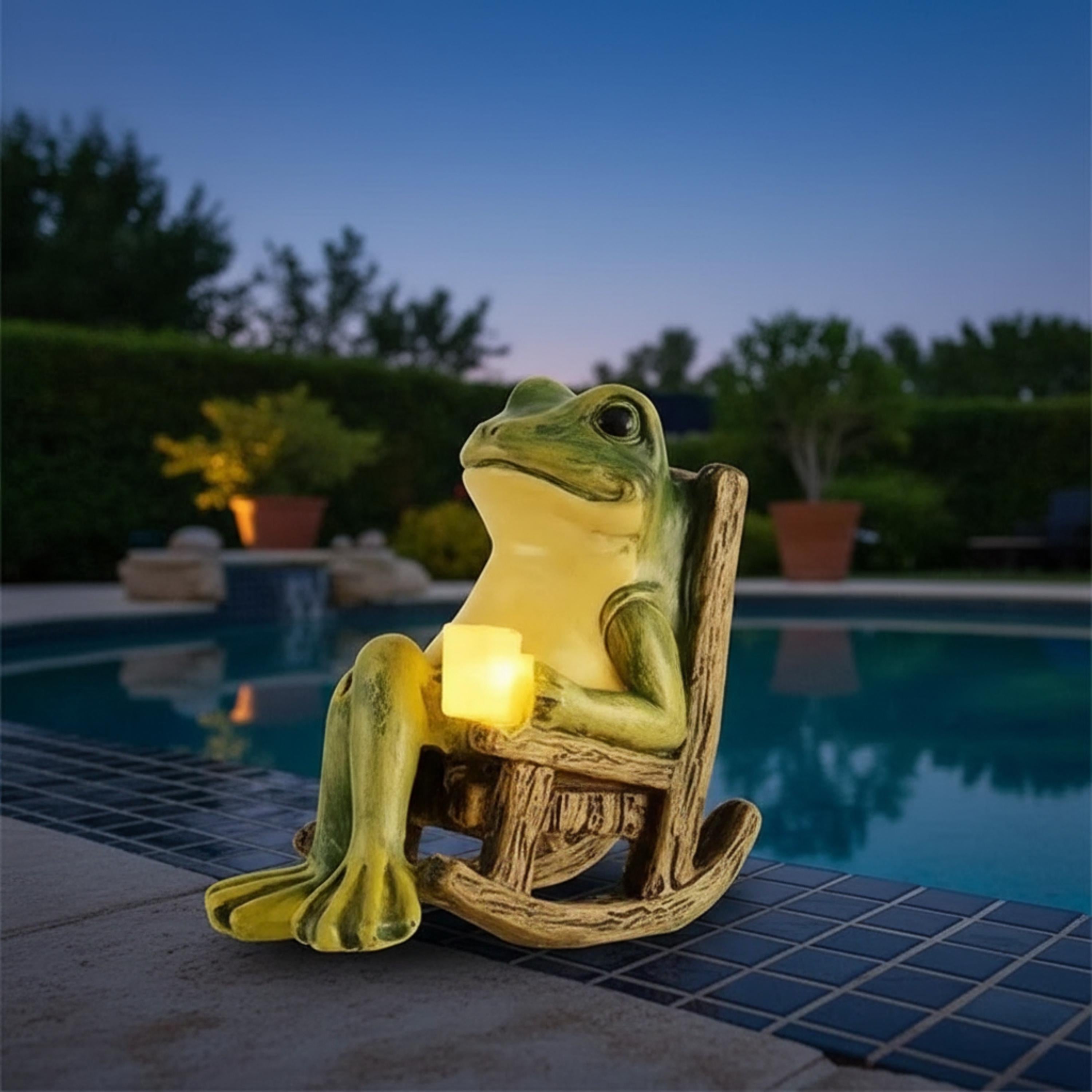 Lighted frog garden ornament displayed beside a swimming pool at dusk