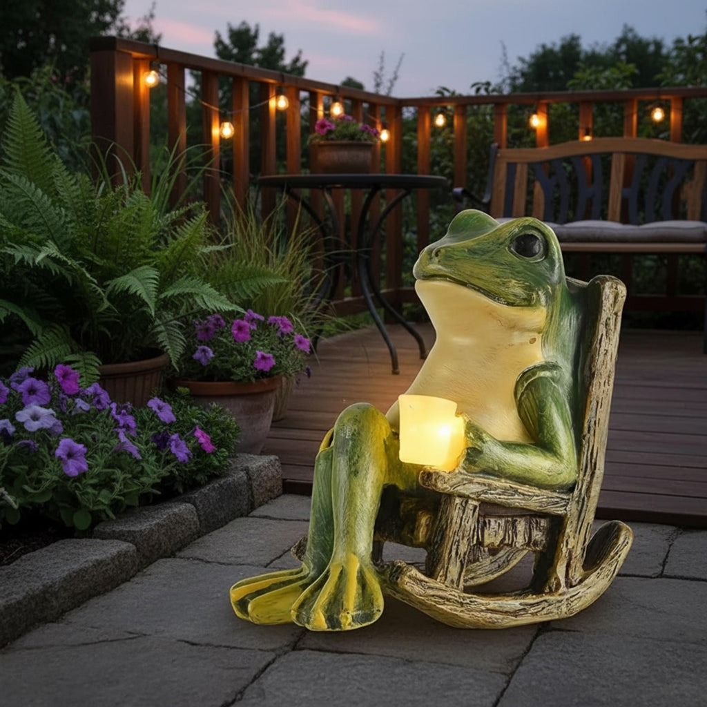 Solar frog garden statue in a rocking chair with glowing lantern on a patio