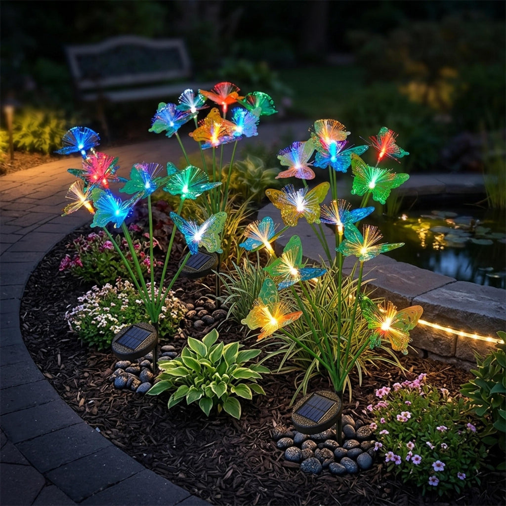 Solar butterfly garden lights illuminating a curved flower bed near a pond