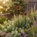 Two rustic metal wildflower stakes among cottage garden blooms