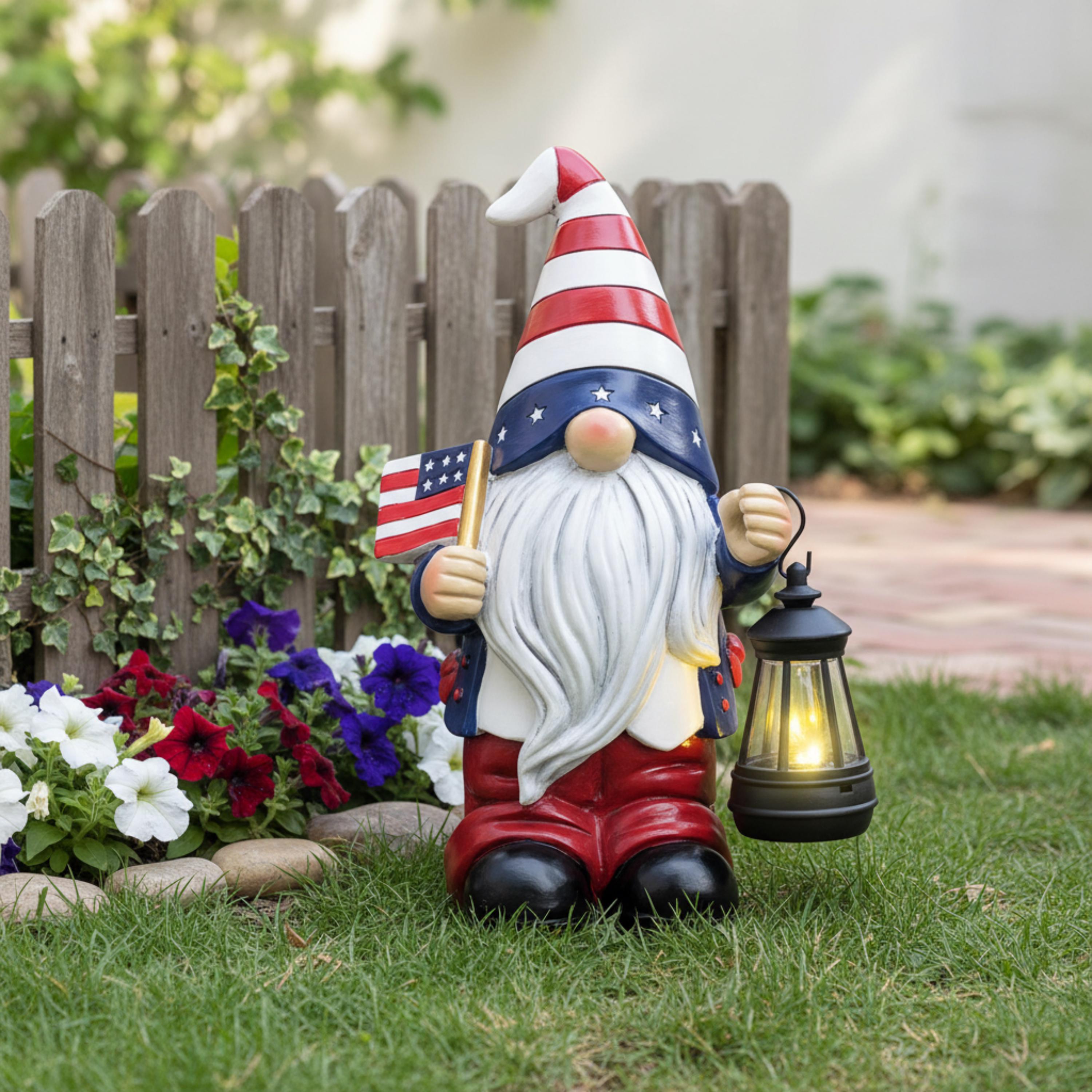 American flag solar gnome displayed near a white garden fence