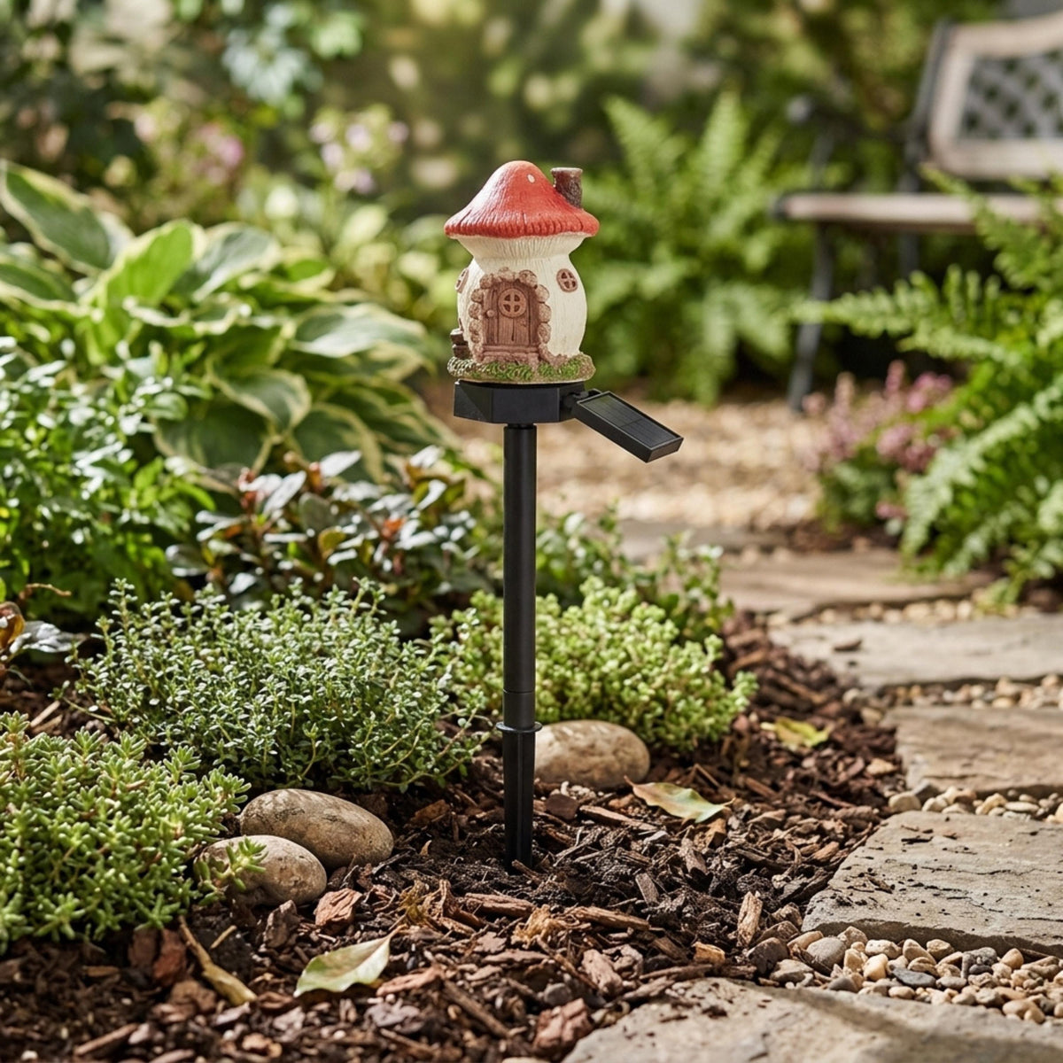 Red mushroom solar fairy house stake in a garden bed