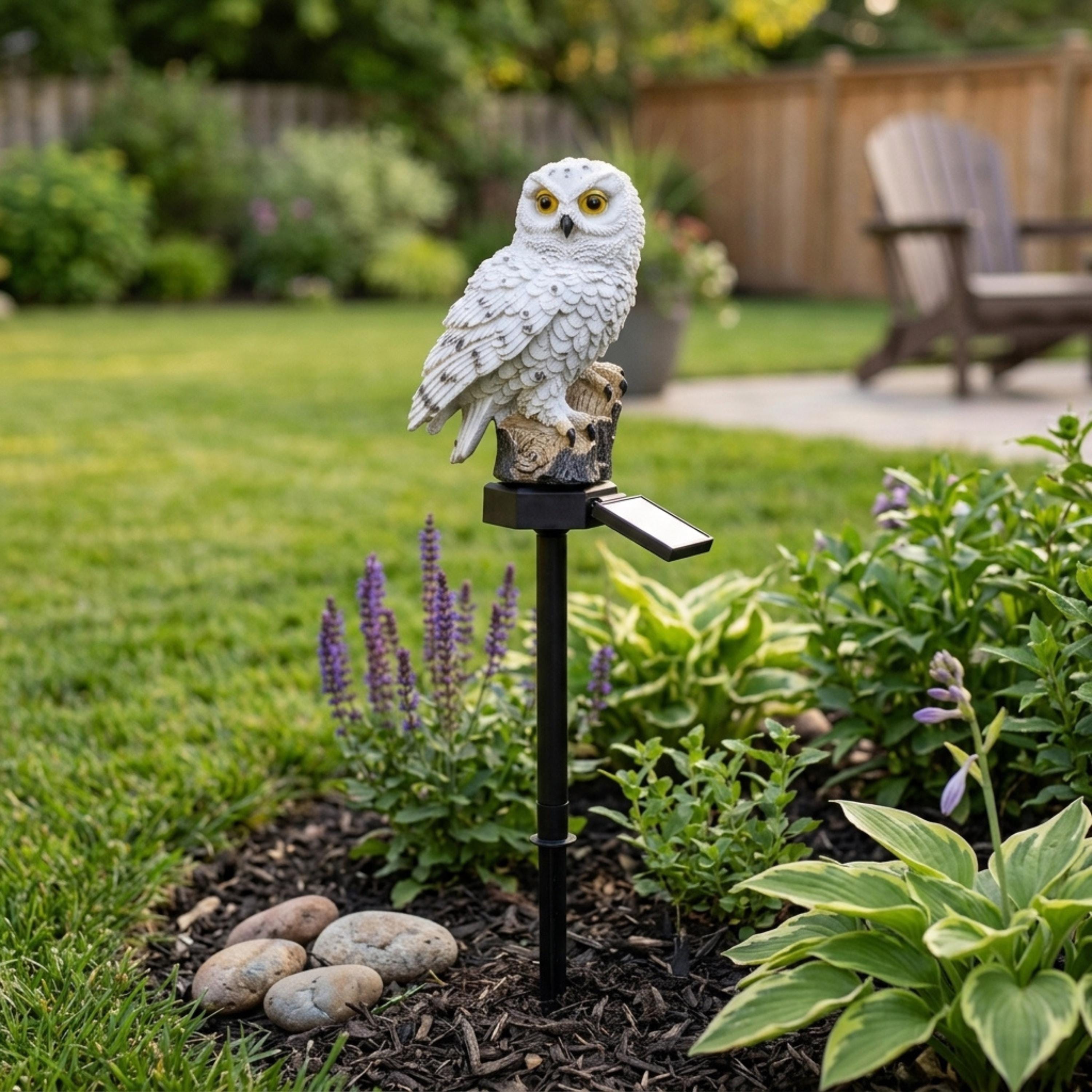 Brown solar owl garden light beside hostas and a stone border