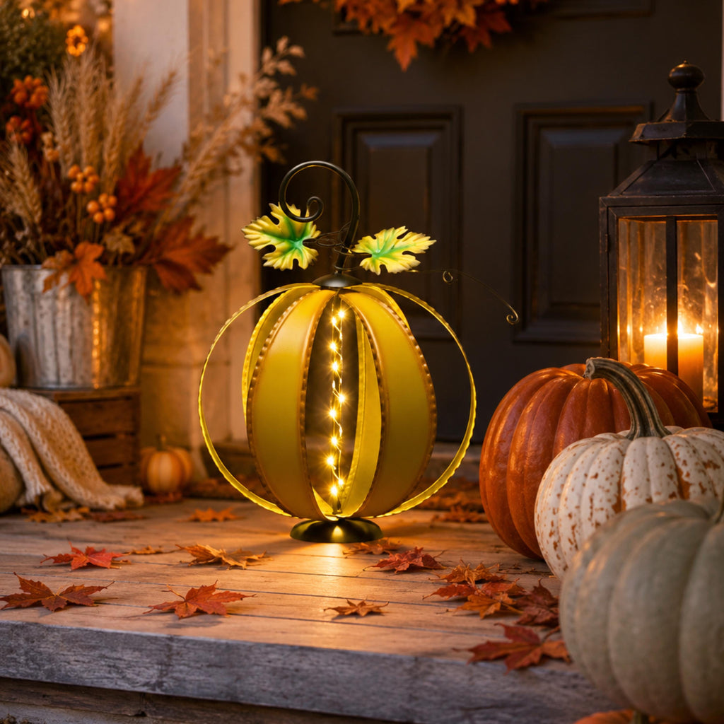 Lighted metal pumpkin with timer displayed among fall leaves