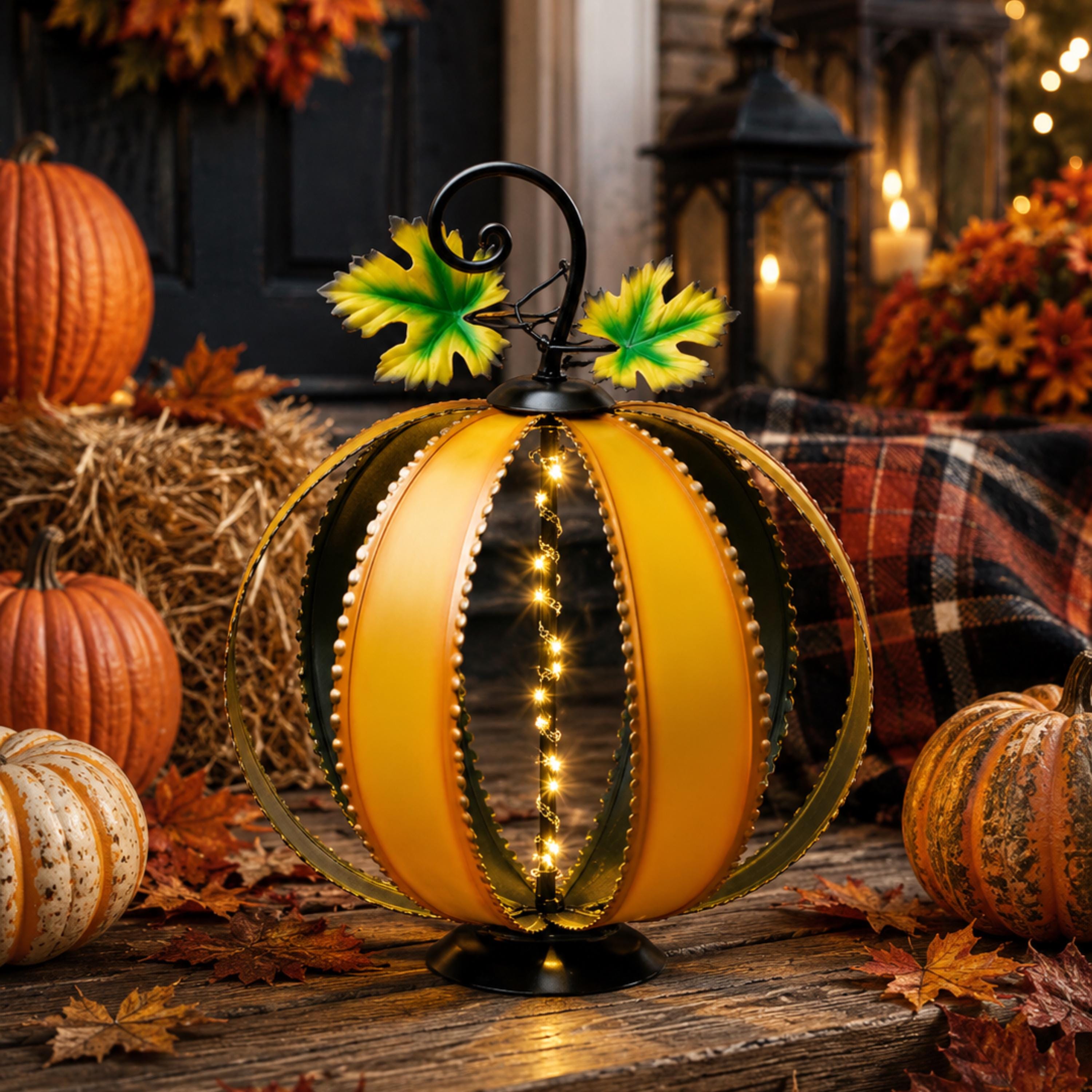 Large lighted yellow metal pumpkin glowing in an autumn porch display