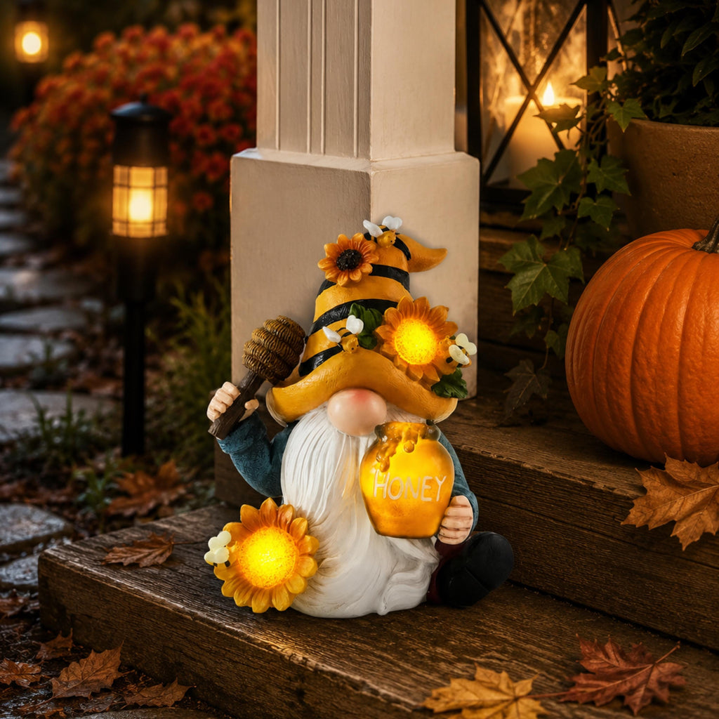Solar bee gnome glowing on porch steps beside autumn pumpkins